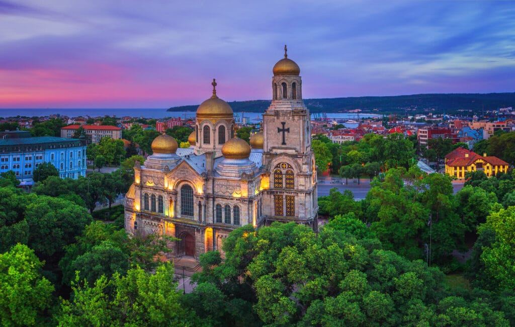 Golden-domed cathedral at dusk above the treetops