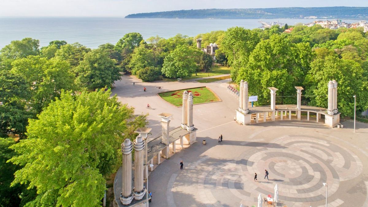 Park entrance with stone columns and a view of the sea