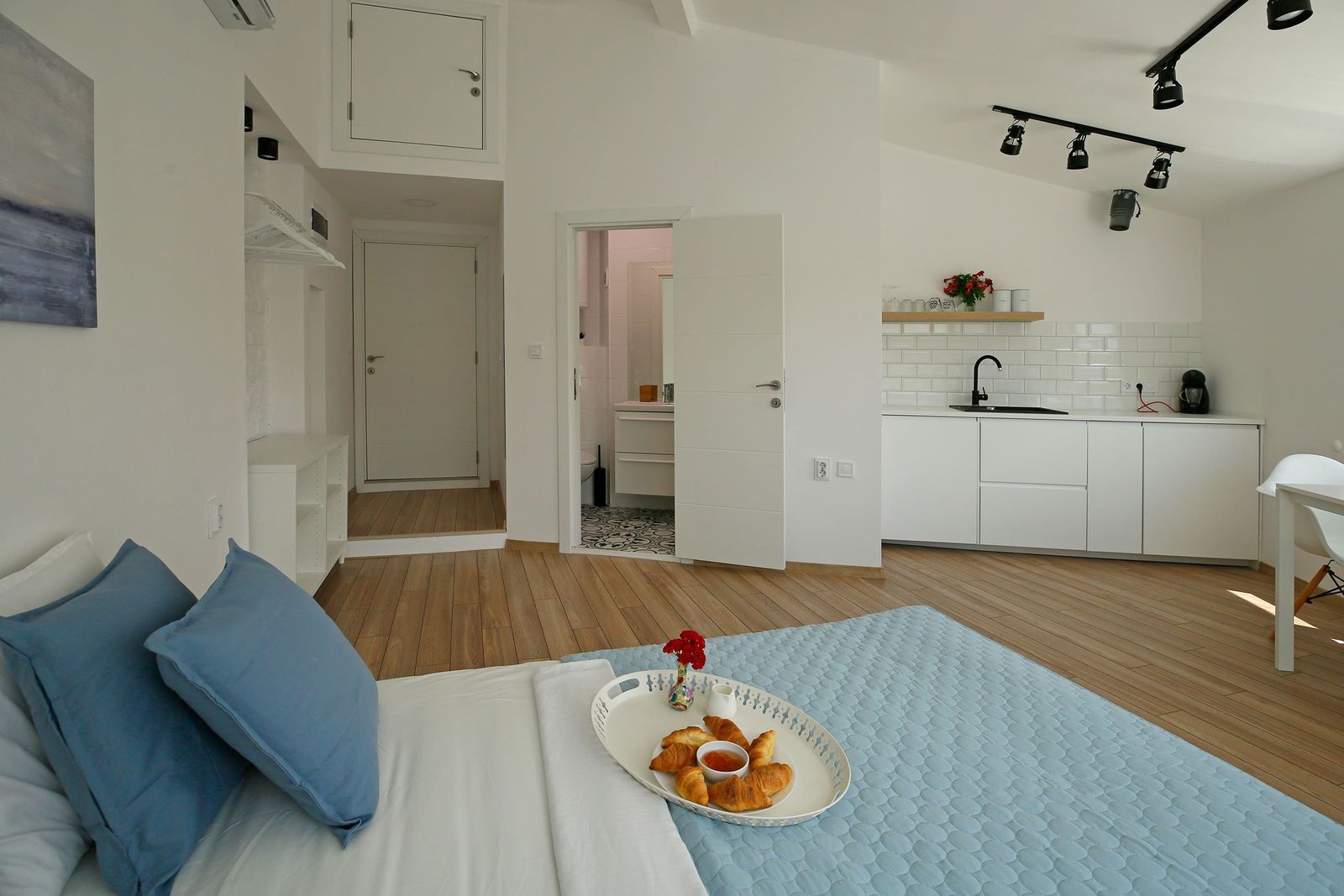 View from the bed towards the bathroom door and kitchenette