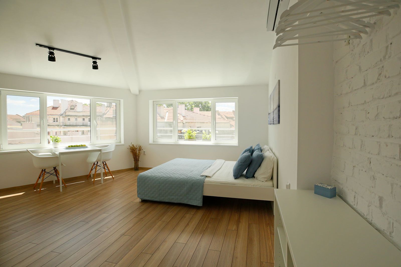 Studio with white brick wall, bed and dining area