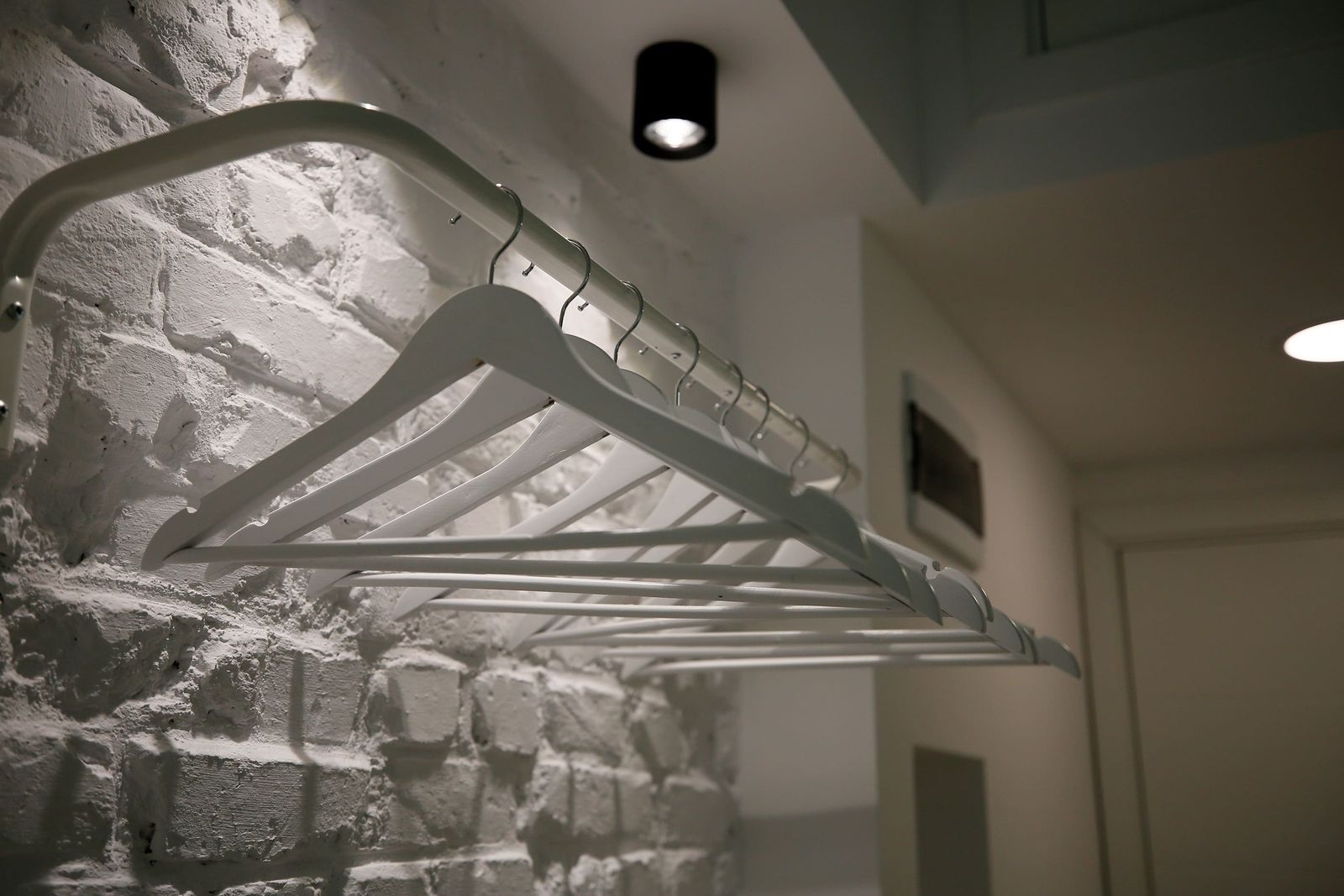White hangers on a rail against a white brick wall