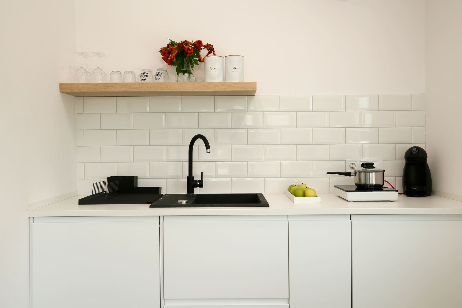 Kitchen counter with black sink, wooden shelf and coffee jars
