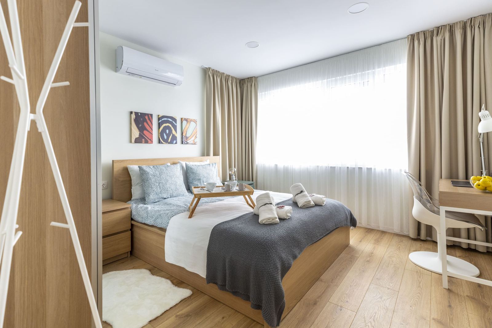 Bedroom with a wooden bed, breakfast tray and butterfly paintings