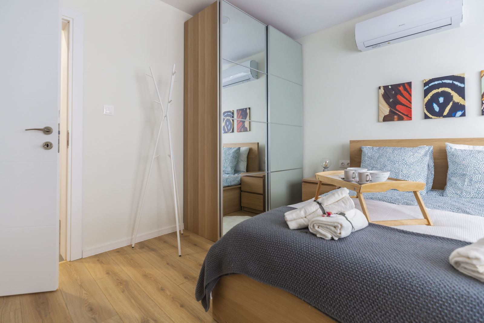 Bedroom with mirrored wardrobe, coat stand and bed with breakfast tray