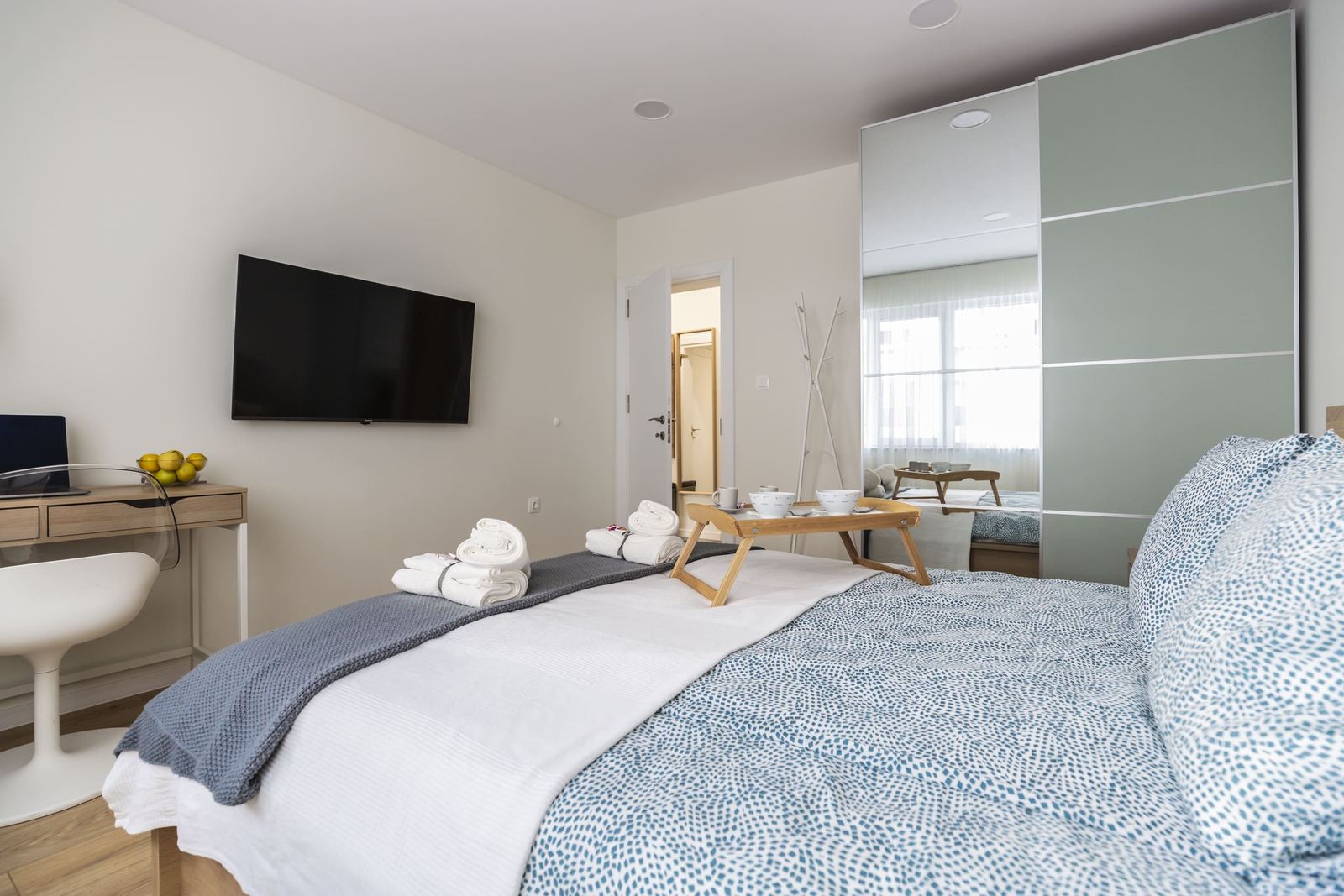 Bed with towels and breakfast tray, TV and mirrored wardrobe