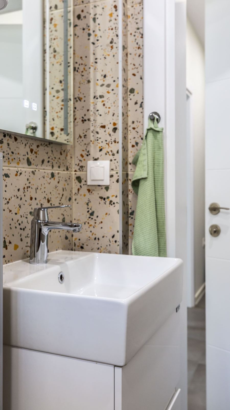 Bathroom sink with terrazzo tiles and a green towel