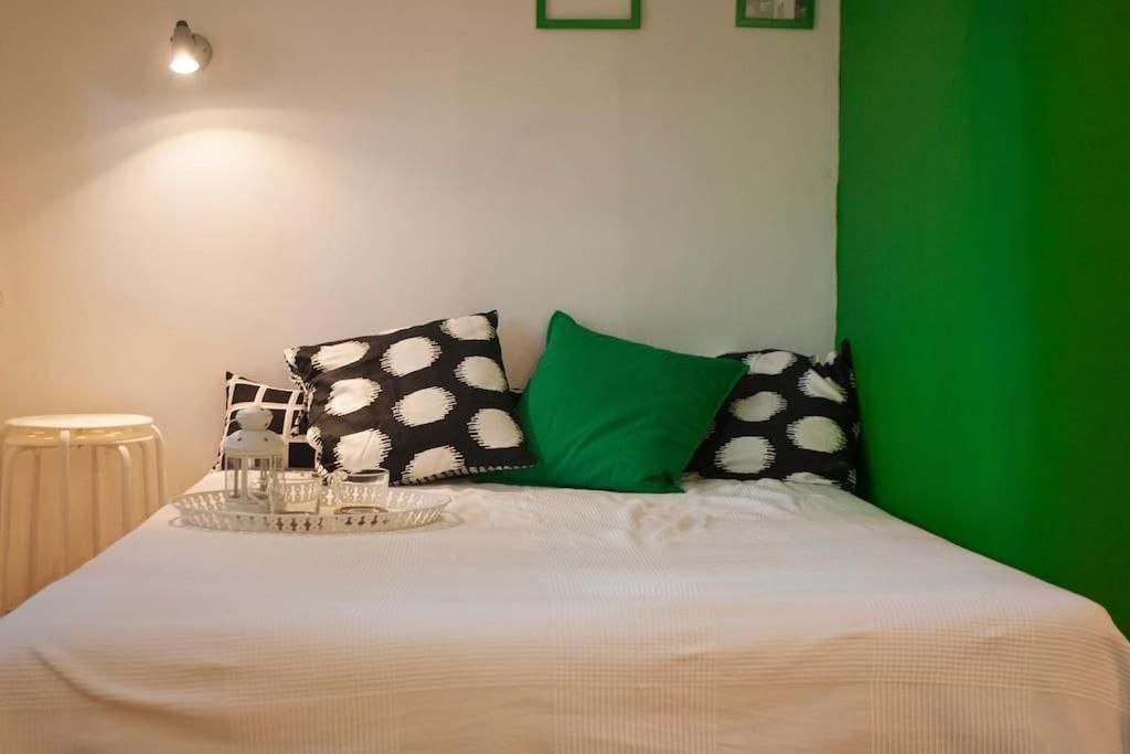 Bed with polka-dot cushions and a green accent wall