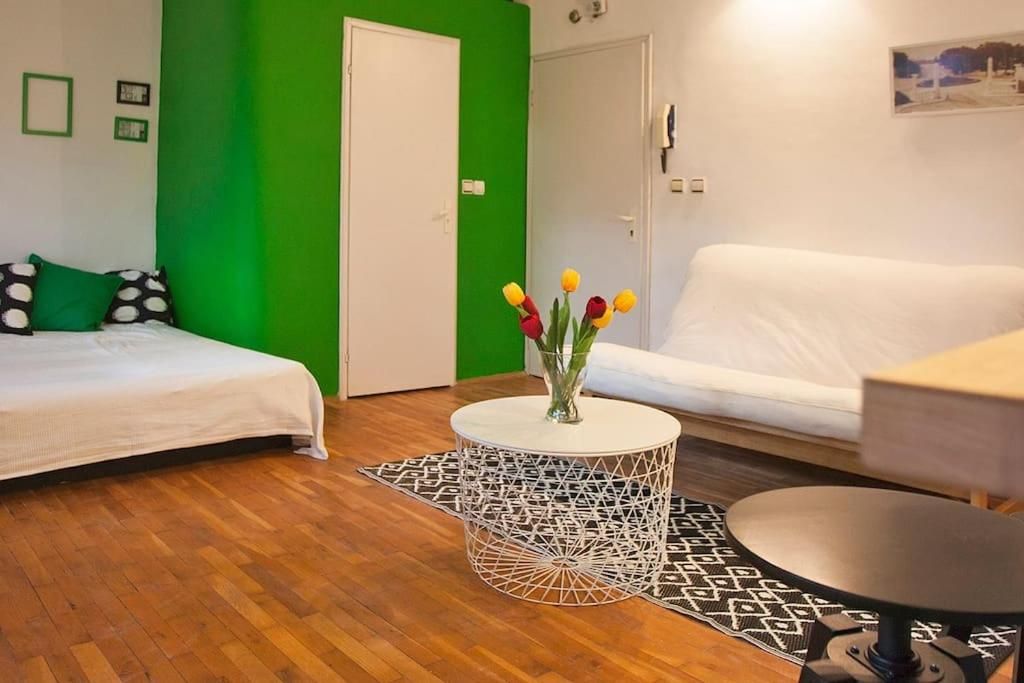 Studio with a bed, futon sofa and a white table with tulips